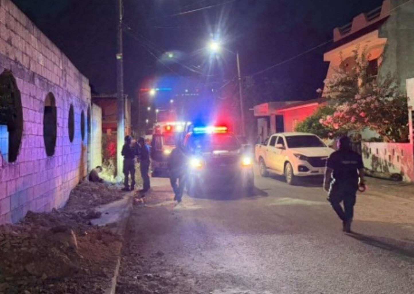 Patrullas y ambulancias estacionadas en una calle de Cancún durante un operativo.